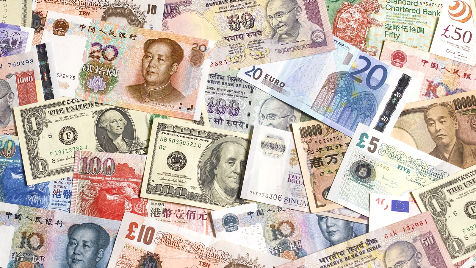 different currencies from around the world laid out on a table, us dollars, chinese yuan and more