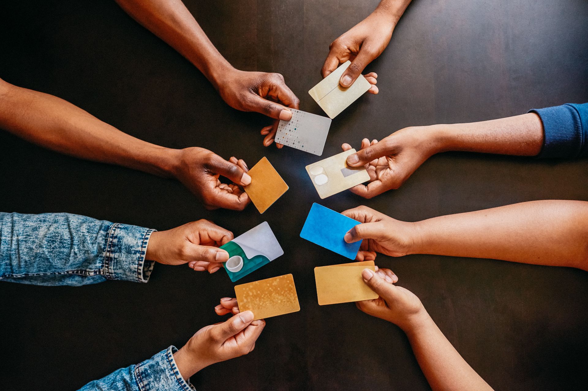 High angle shot of a group of unrecognizable people holding out their credit cards over a table